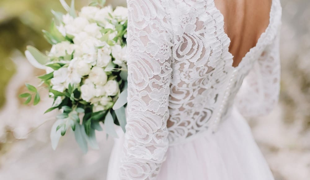 A bride in a white wedding dress holding a bouquet of flowers.
