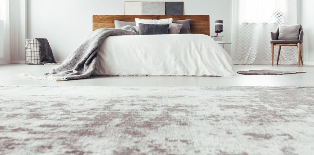 A bedroom with white walls and a grey rug.